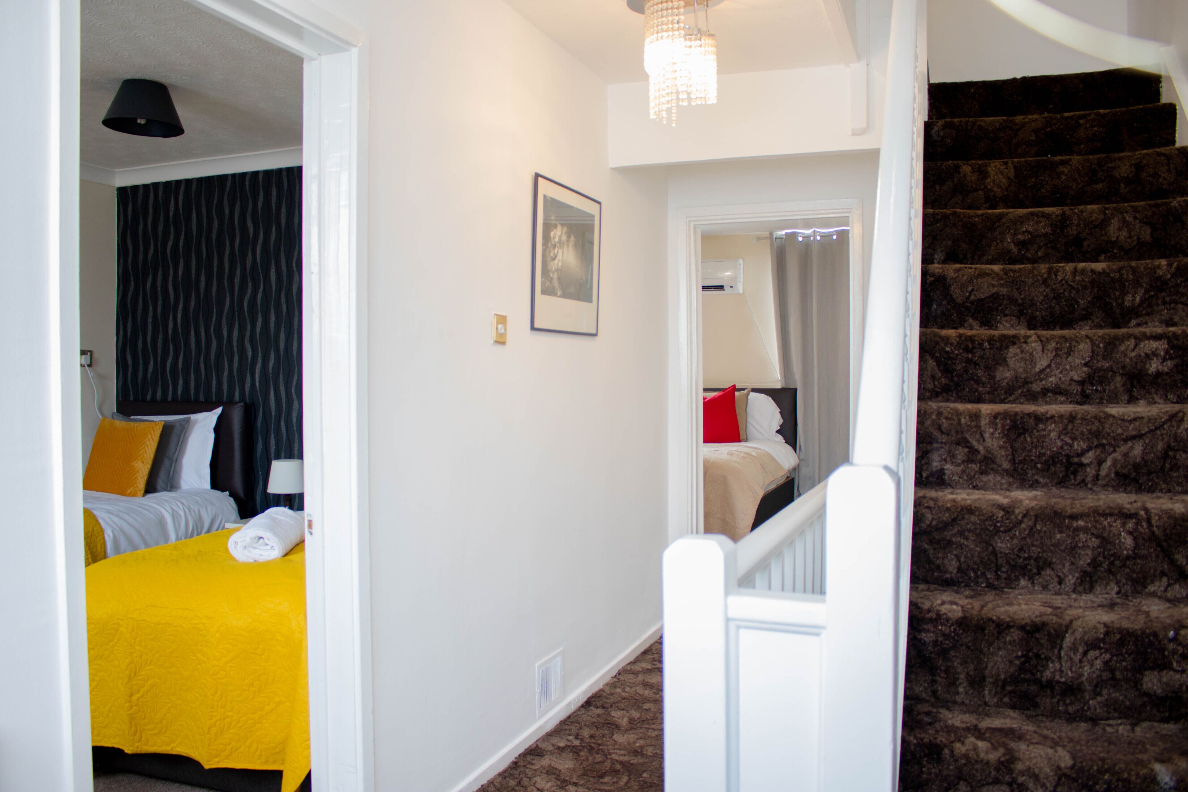 A hotel room with a bed, a nightstand, a chair, a desk, and a staircase.