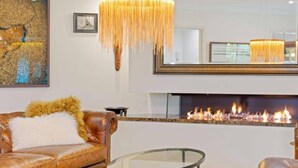 A modern living room with a fireplace, leather sofas, a glass coffee table, and a large mirror. - Riverside Breeze - private luxury family retreat with pool (Port Macquarie)