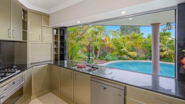 A modern kitchen with a large window overlooking a pool and tropical garden. - Riverside Breeze - private luxury family retreat with pool (Port Macquarie)