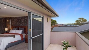 A bedroom with a bed, a nightstand, a lamp, and a window. - Riverside Breeze - private luxury family retreat with pool (Port Macquarie)