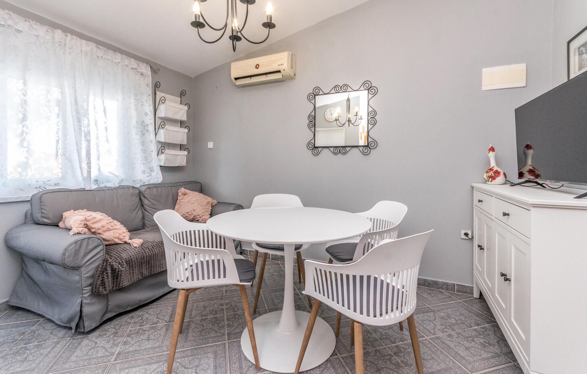 A cozy living area with a grey sofa, a white round table, and matching chairs.