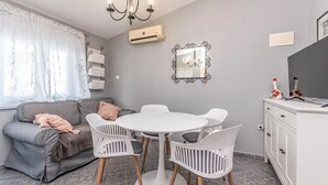 Una sala acogedora con un sofá gris, una mesa redonda blanca y sillas a juego.