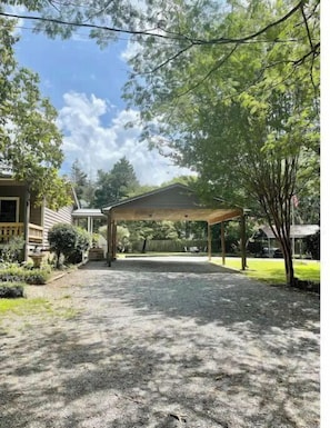 A covered patio area with a gravel driveway leading to a house.