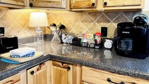 A kitchen with wooden cabinets, a granite countertop, a Keurig coffee maker, a coffee pot, a lamp, and kitchen utensils. - Etowah River, Berry & Shorter College, Tennis, Trails-3 miles from Broad St. (Rome)