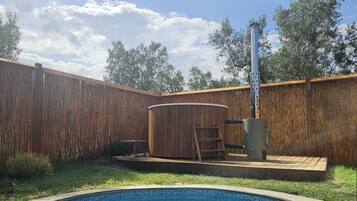 Un patio trasero con un jacuzzi, una piscina y una valla de madera.