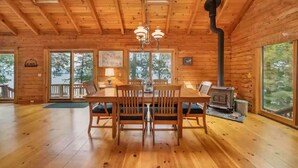 A wooden cabin with a dining area, a fireplace, and large windows. - Waterfront at Winnipesaukee with incredible views!! Boat Required (Alton)
