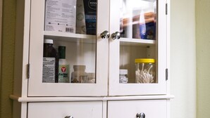 A white cabinet with glass doors containing various items like bottles and containers. - Peaceful Paradise 3BR Cottage Getaway (Homer)