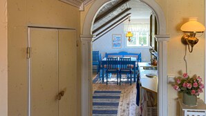 A hallway with a wooden floor, a blue and white checkered tablecloth-covered table, and blue chairs.