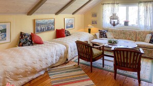 A cozy room with two beds, a sofa, a dining table, and a chandelier.