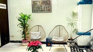 A small outdoor seating area with two wicker chairs, a potted plant, and a framed picture on the wall. - HoM Balderas - Hostel (Mexico City)