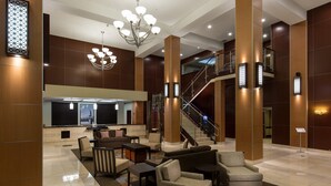 A spacious lobby with a high ceiling, a chandelier, a staircase, and a seating area with sofas and tables. - 1 Bedroom | Modern, Sophisticated Suite + Shuttles (Las Vegas)