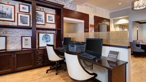 A business center with two desks, chairs, a computer, and a printer.