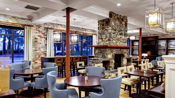 A spacious restaurant with a stone fireplace, wooden flooring, and modern seating arrangements.