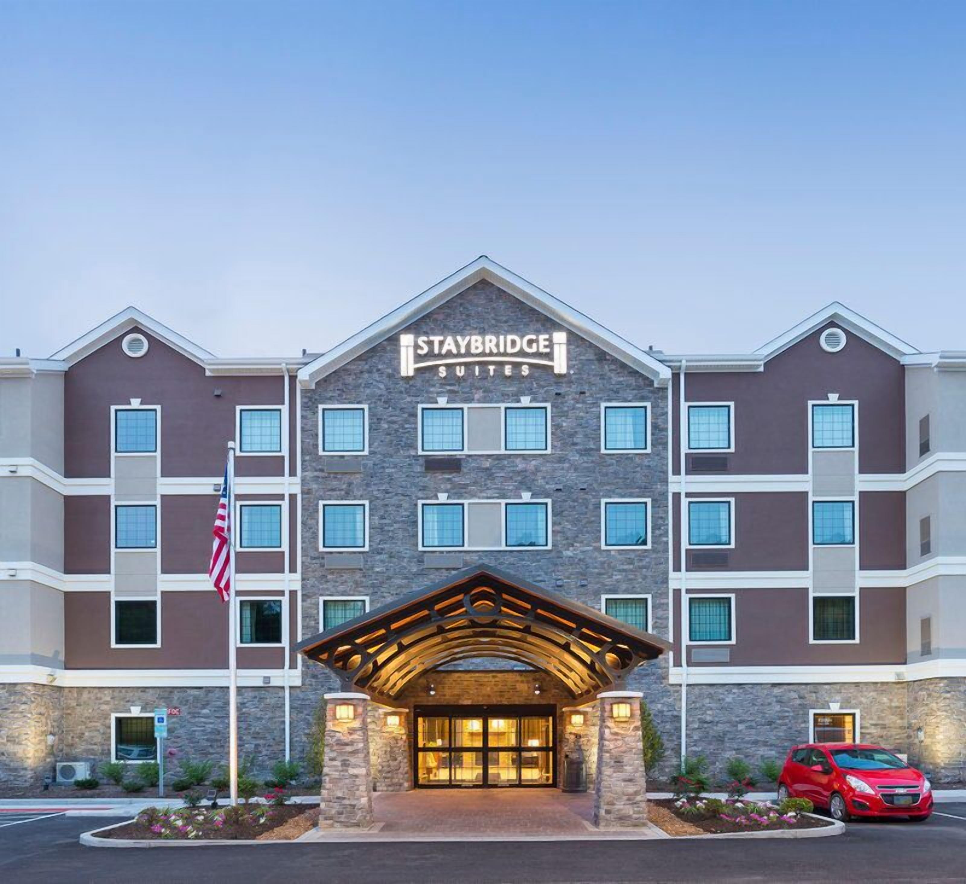 A Staybridge Suites hotel with a stone facade, multiple windows, and a prominent entrance with a covered porch.