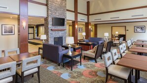 A hotel lobby with a stone fireplace, multiple seating areas, and a television mounted on the wall. - 1 Bedroom | Breakfast Buffet. Pool & Hot Tub (Canton)