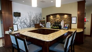 A hotel lobby with a granite bar, seating area, and a stone accent wall.