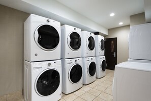 Une buanderie équipée de plusieurs machines à laver superposées.