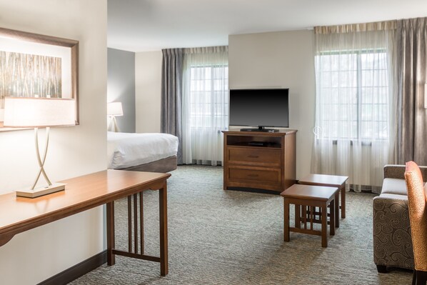 A hotel room with a bed, a TV, a desk, a chair, and a sofa.