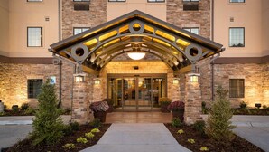 A hotel entrance with a stone facade, a covered entrance area, and potted plants.