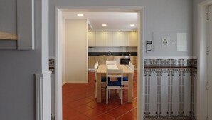 Eine moderne Küche mit weißen Schränken, einer schwarzen Arbeitsplatte und einem Essbereich mit einem Holztisch und Stühlen.