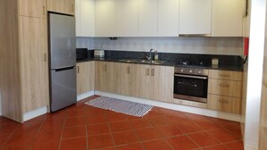 Eine moderne Küche mit hellen Holzschränken, einem Edelstahl-Kühlschrank, einem Gasherd und einem eingebauten Backofen.