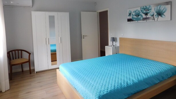 Ein Schlafzimmer mit Bett, Stuhl, Kleiderschrank und einem Bild an der Wand.