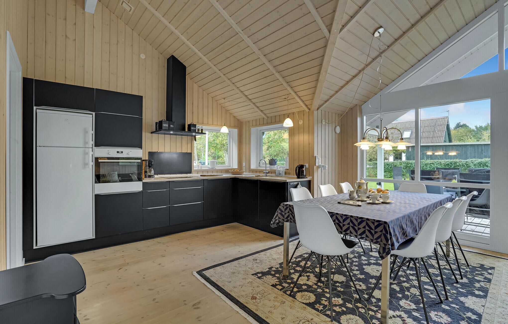 Une cuisine moderne avec des meubles de rangement noirs et blancs, un four encastré et une grande fenêtre donnant sur un jardin.