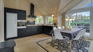 Uma cozinha moderna com armários preto e branco, forno embutido e uma grande janela com vista para um jardim.