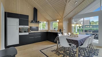 Une cuisine moderne avec des meubles de rangement noirs et blancs, un four encastré et une grande fenêtre donnant sur un jardin.