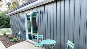A patio with two green metal chairs and a table, a sliding glass door, and a metal wall. - Two-Seventeen, a cozy Wetumpka home (Wetumpka)