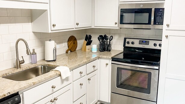 A modern kitchen with white cabinets, stainless steel appliances, and a wooden floor. - Two-Seventeen, a cozy Wetumpka home (Wetumpka)