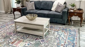 A living room with a grey sofa, a coffee table, patterned rug, and a painting on the wall. - Two-Seventeen, a cozy Wetumpka home (Wetumpka)