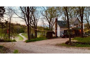A rural road leading to a house surrounded by trees. - The Napping Farm (Dane)
