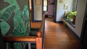 A wooden staircase leading to a landing with a view of a hallway.