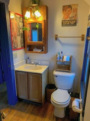 A compact bathroom with a wooden cabinet, a sink, and a toilet.