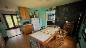 A kitchen with wooden cabinets, a dining table with chairs, and a chalkboard wall with writing.