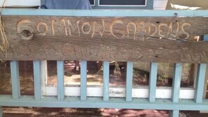 A wooden sign with carved text on a porch railing.