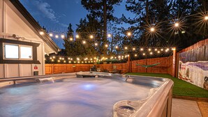 A hot tub with a wooden deck and a mural on the wall.