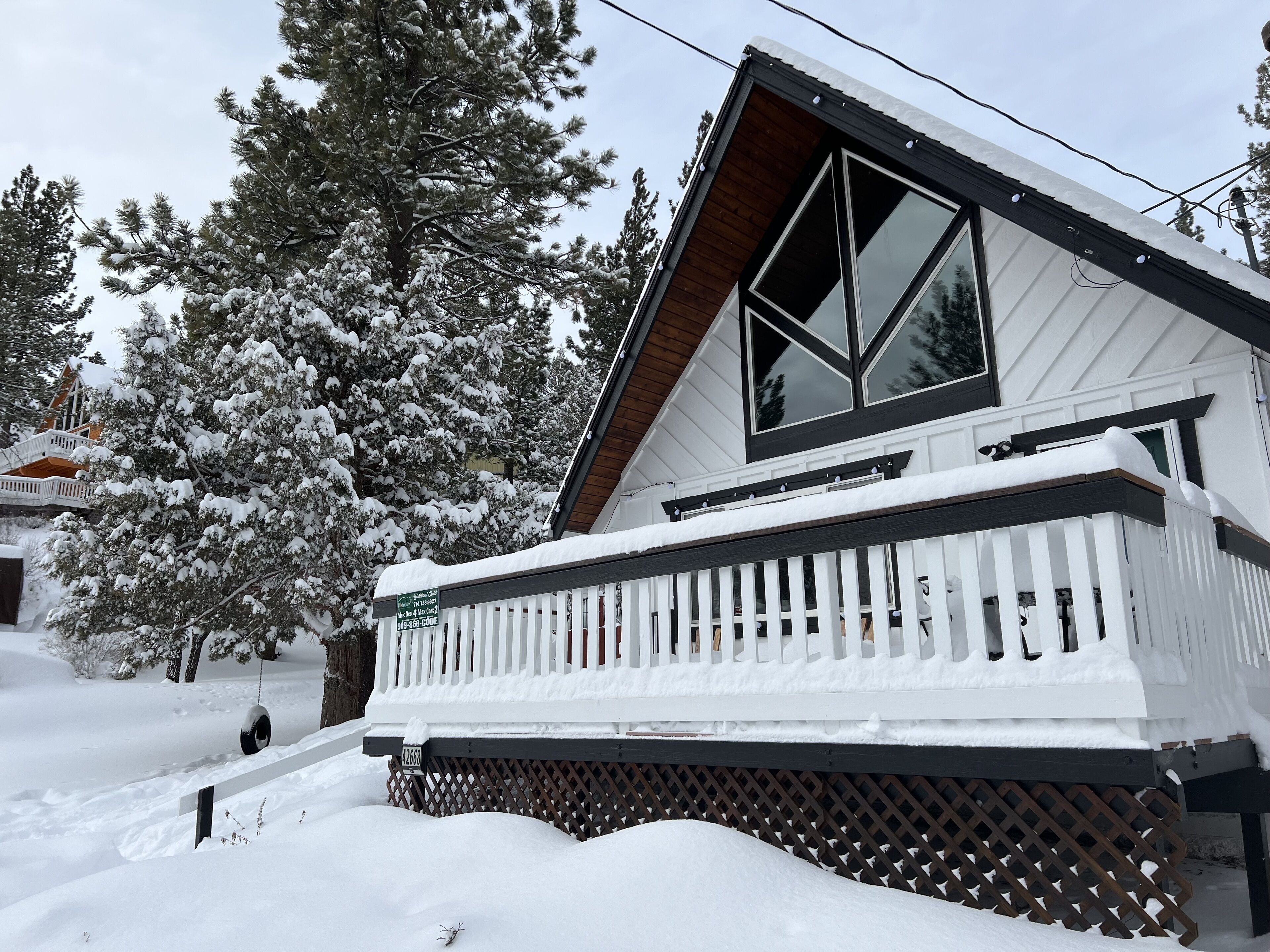 Een huis bedekt met sneeuw, met een witte veranda en een groot raam.