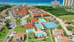 A resort with multiple buildings, a swimming pool, tennis courts, and a view of the ocean. - First Floor • Walk to Beach • Sleeps 6 (Panama City Beach)