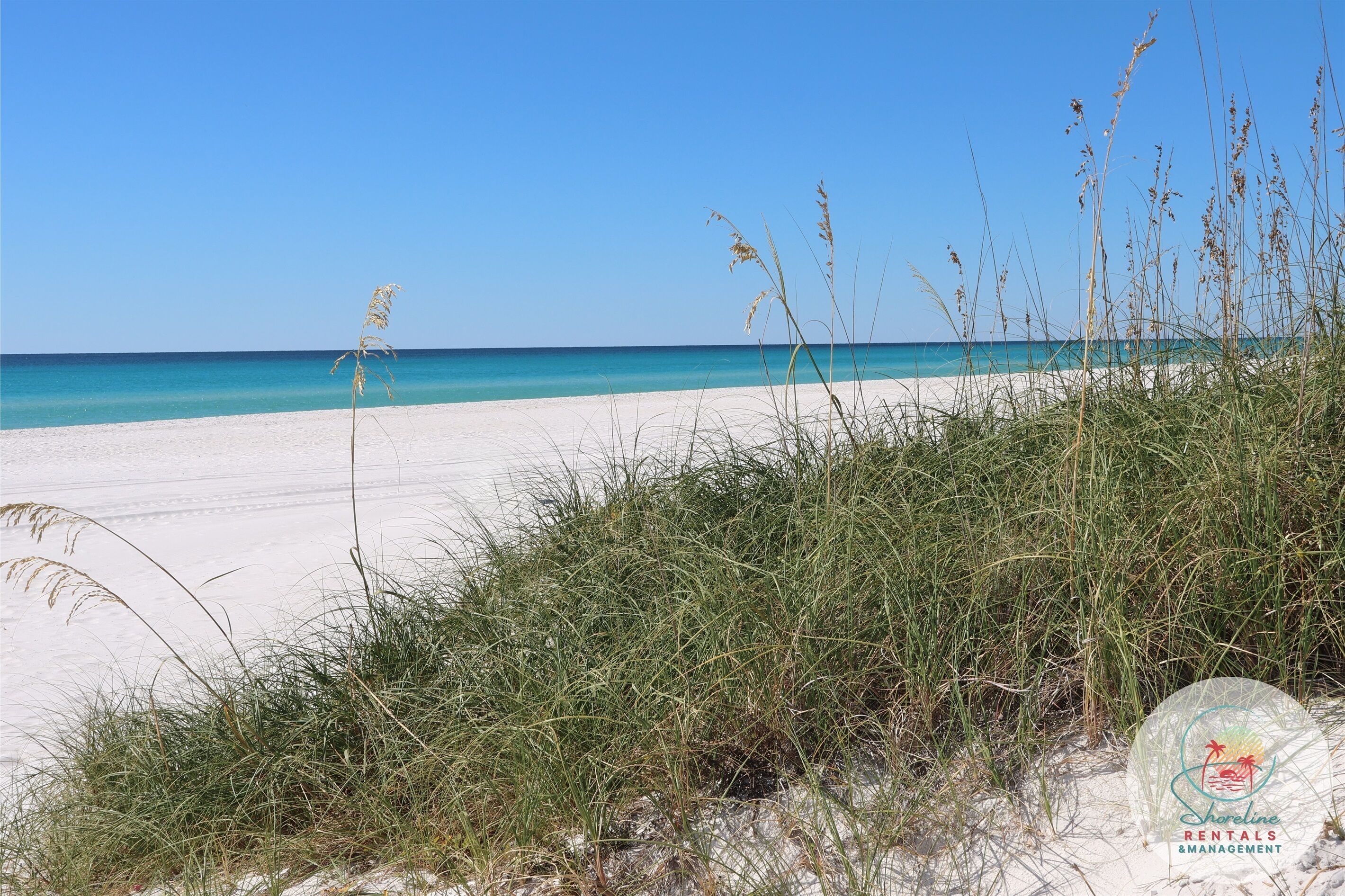 A beach with clear blue water and white sand.