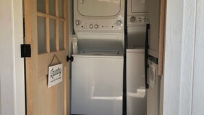 A laundry room with a sign indicating it contains a wash and dry fold press. - Studio B. Katie and Steve Riley Apartment (Breaux Bridge)