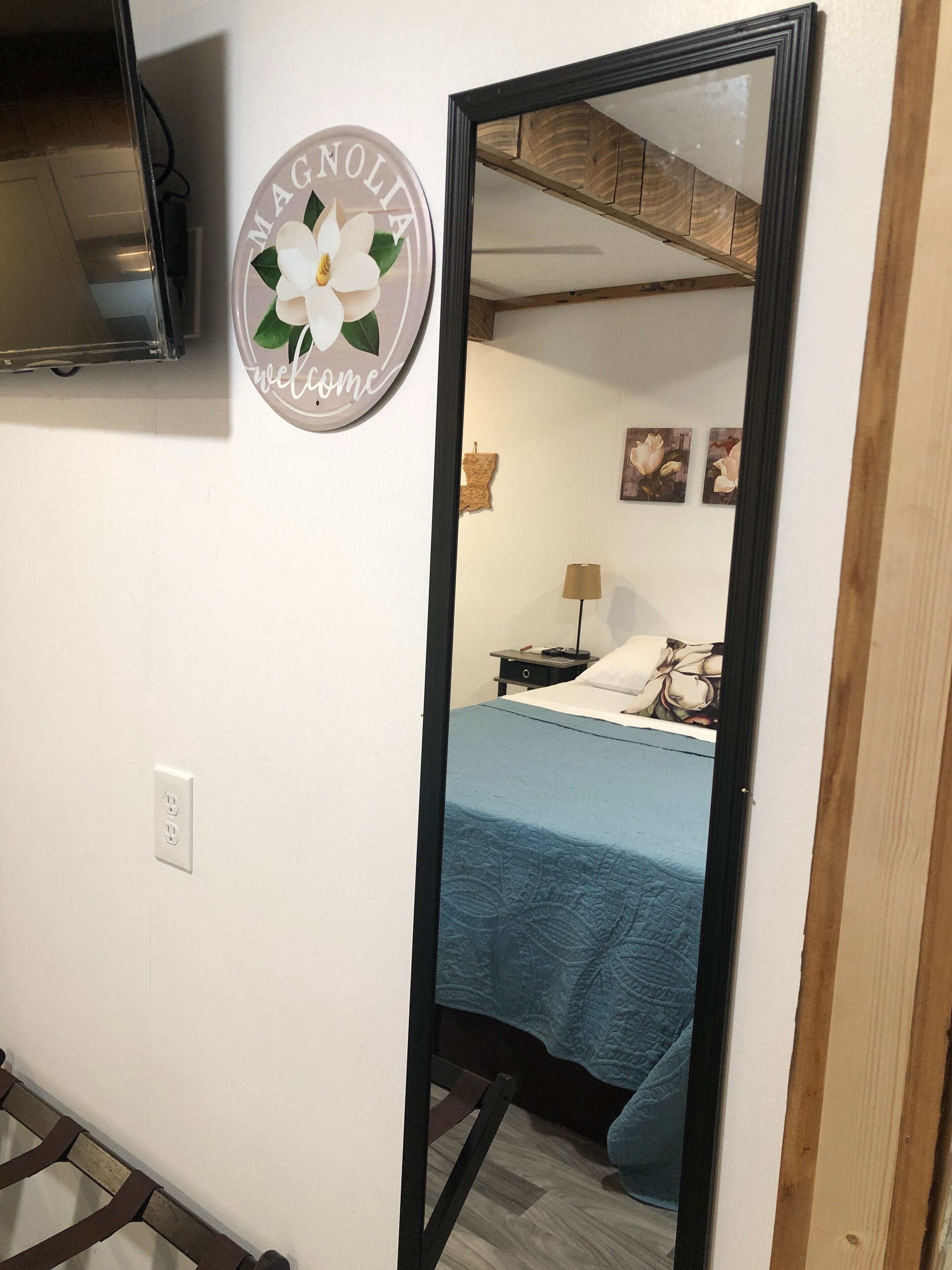 Un dormitorio con una cama, una mesita de noche, una lámpara y un televisor montado en la pared.