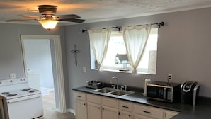 A kitchen with white cabinets, a microwave, a toaster, and a stove.