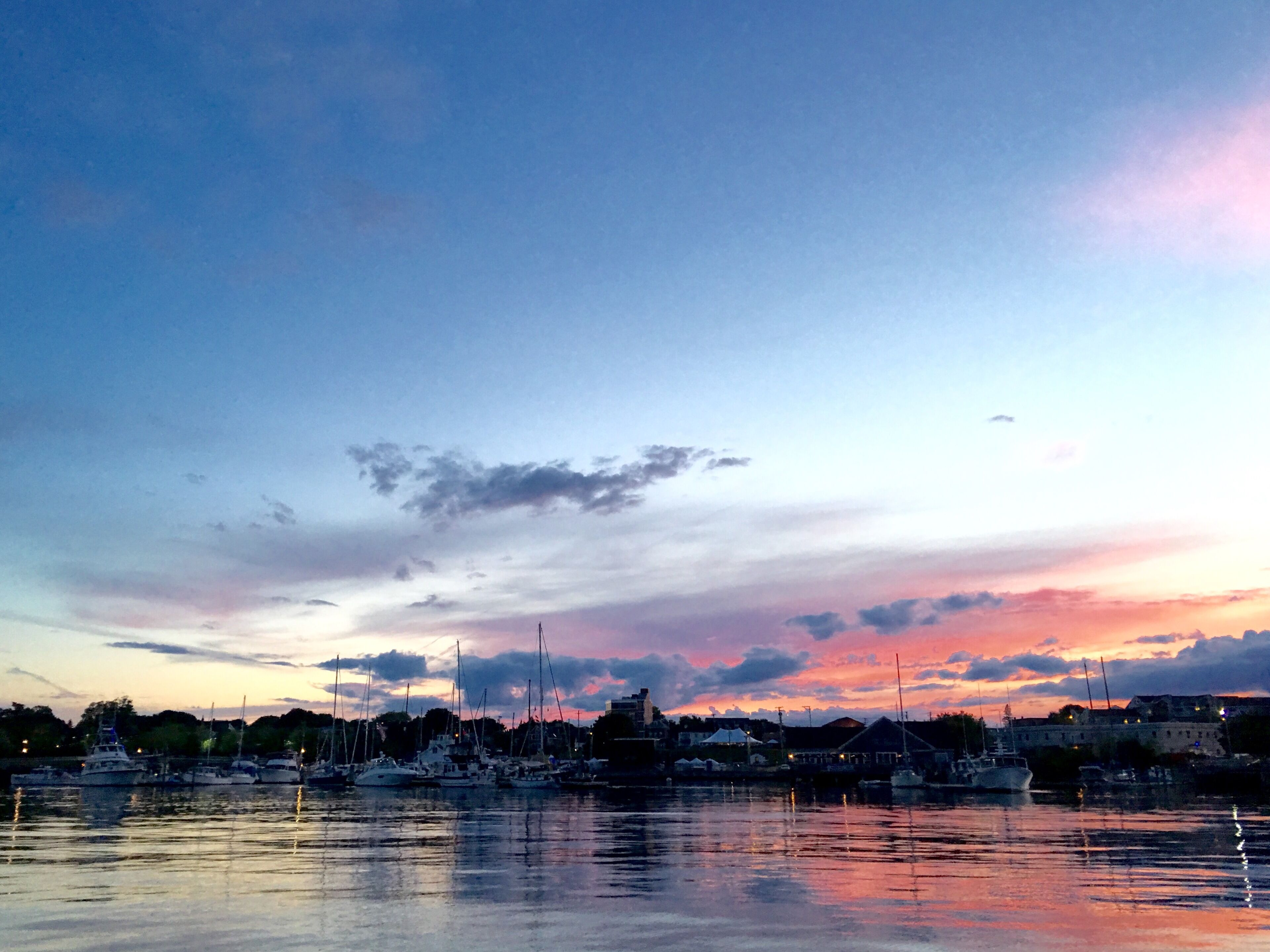 A marina with boats docked, a clear sky, and a distant building.