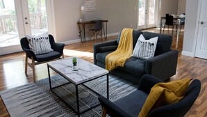 A living room with a sofa, armchairs, a coffee table, and a desk.