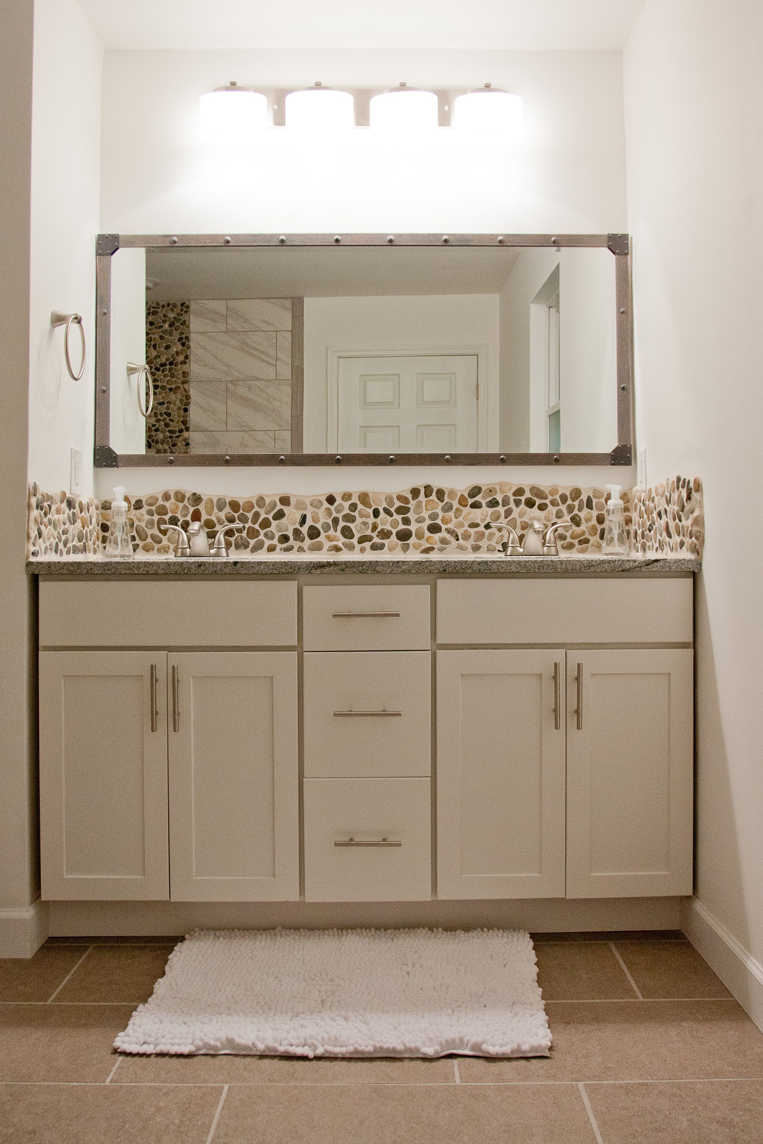 A bathroom with a vanity, a mirror, and a tiled backsplash.