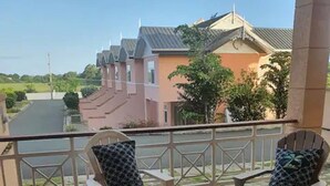 A balcony with two chairs and a small table, overlooking a residential street. - Stunning townhouse in gated community -10 minutes from three beaches. (Mount Pleasant)