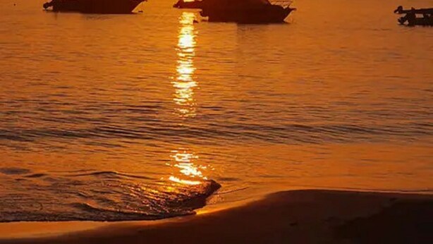 A sunset over a calm sea with boats. - Stunning townhouse in gated community -10 minutes from three beaches. (Mount Pleasant)