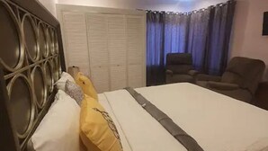 A neatly made bed with a headboard, a chair, and a wardrobe in a room with a ceiling fan. - Stunning townhouse in gated community -10 minutes from three beaches. (Mount Pleasant)